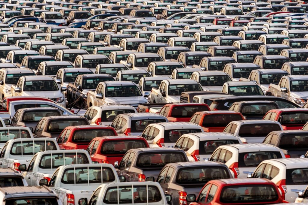 La imagen muestra un parqueadero lleno de carros alineados.