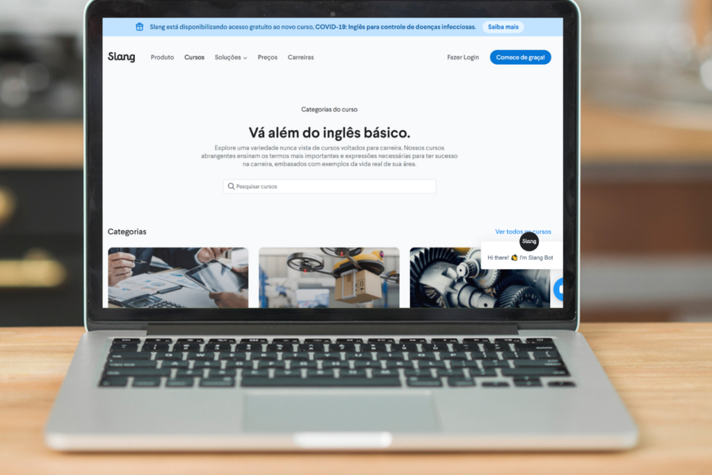 Laptop mostrando a plataforma de cursos da Slang com a frase central “Vá além do inglês básico”. Na Slang, você aprende como melhorar o seu listening.